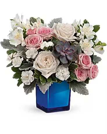Romance Bouquet - Soft pink and white roses paired with white alstroemeria create a gentle, romantic birthday bouquet or anniversary arrangement that also reads as a comforting sympathy spray. The rounded, full design centers the pastel blooms so the recipient feels warmly seen; the vivid blue glass vase gives a modern contrast that makes the soft colors pop and lends an air of thoughtful elegance.  Silvery-gray foliage and touches of greenery add soft texture and a cool-toned balance to the pinks and whites, while the blue glass vase anchors the composition with a clear, luminous presence. Designed to sit beautifully on a bedside table, mantel, or dining table, the arrangement arrives gift-ready in the vase - simple care is keeping the water fresh and trimming stems every few days so the roses and alstroemeria last their longest.