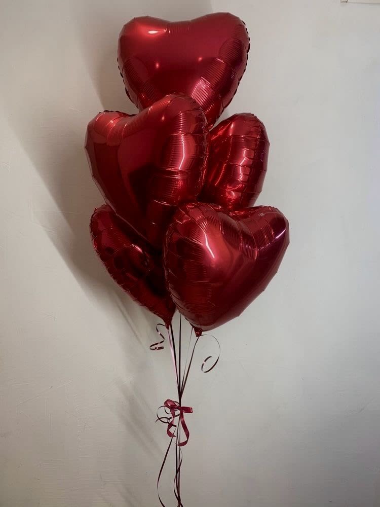 Cluster of red heart-shaped balloons tied with ribbon