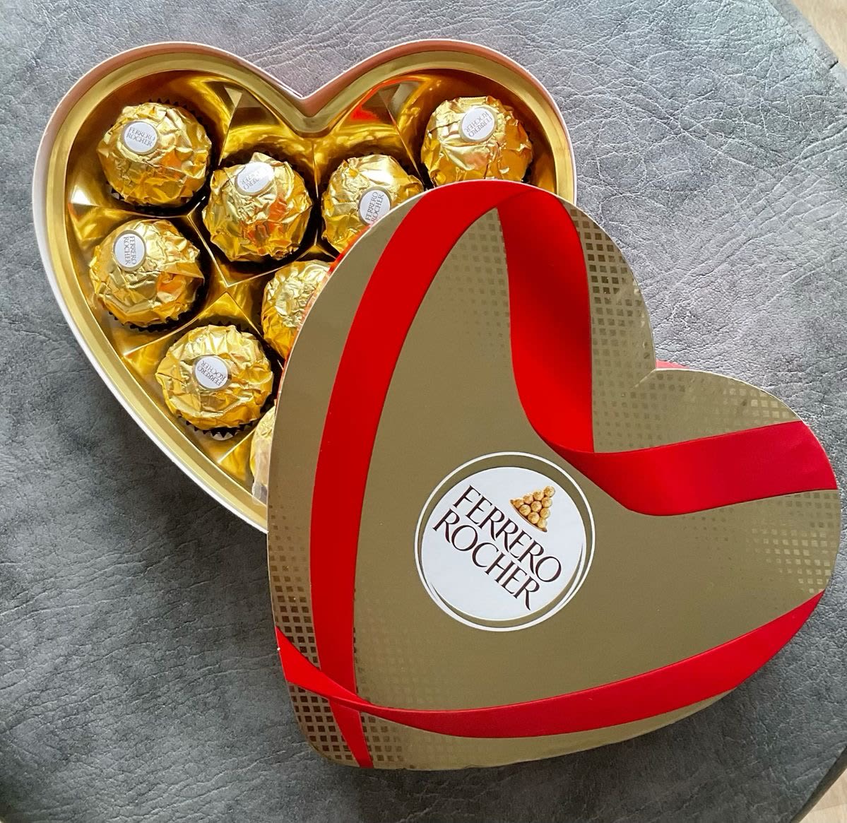 Heart-shaped box of gold-wrapped chocolates with a red ribbon