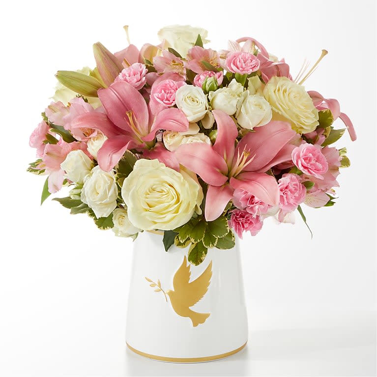Pink and white flower bouquet in a white vase with a gold dove design
