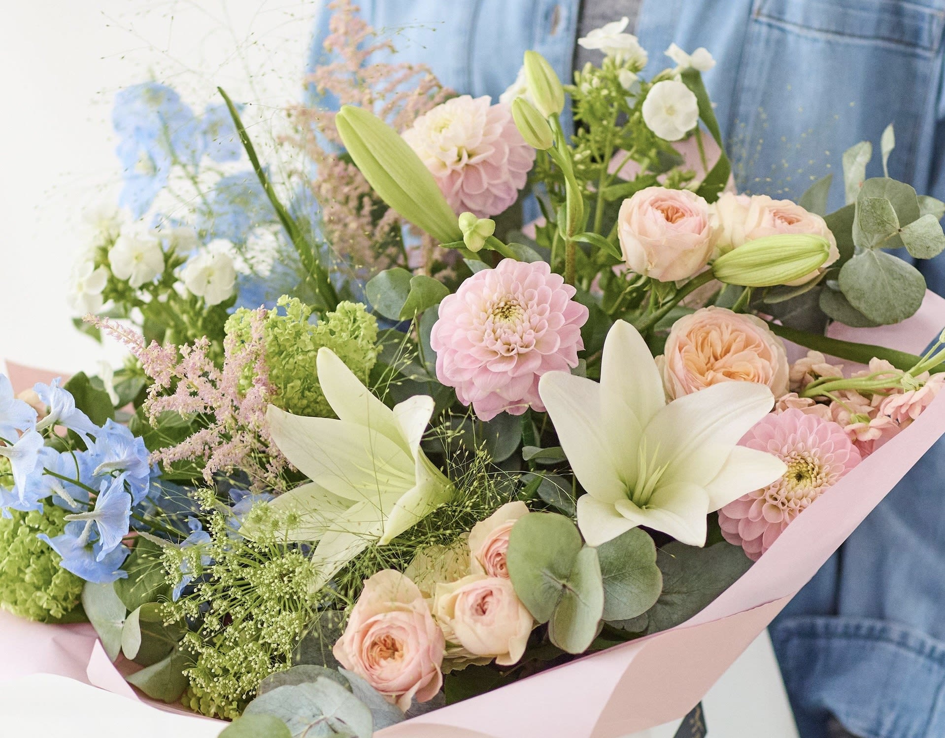 Pastel bouquet with lilies, roses, and pink blooms wrapped in pink paper