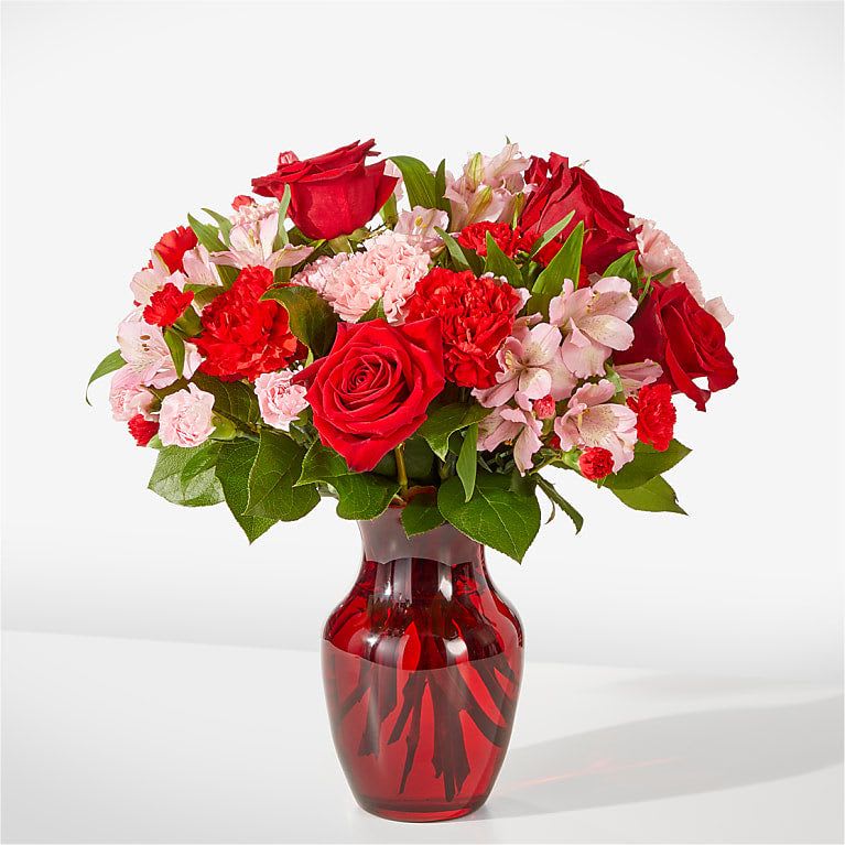 Red roses and pink carnations in a red glass vase