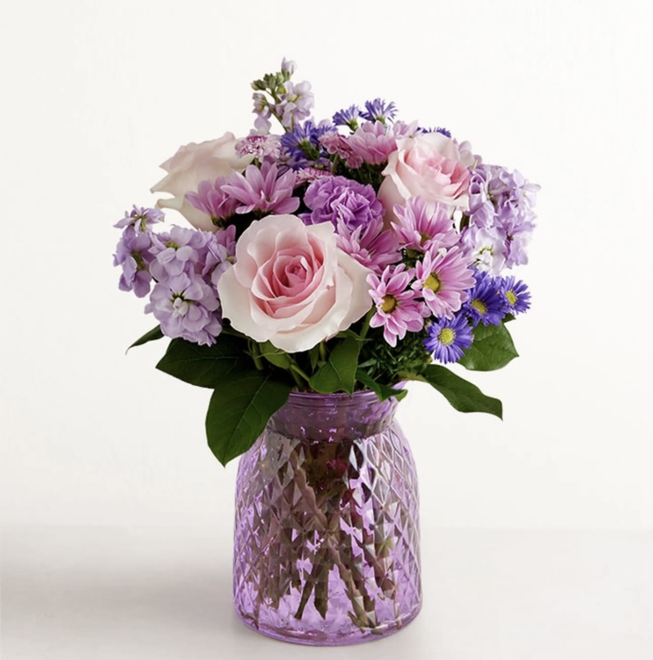 Pink and lavender mixed bouquet in a purple glass vase