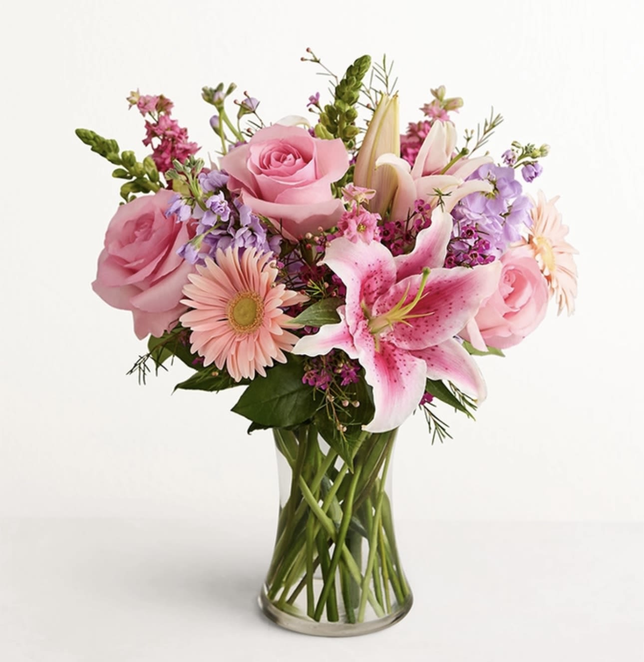 Pink roses and lilies arranged in a clear glass vase