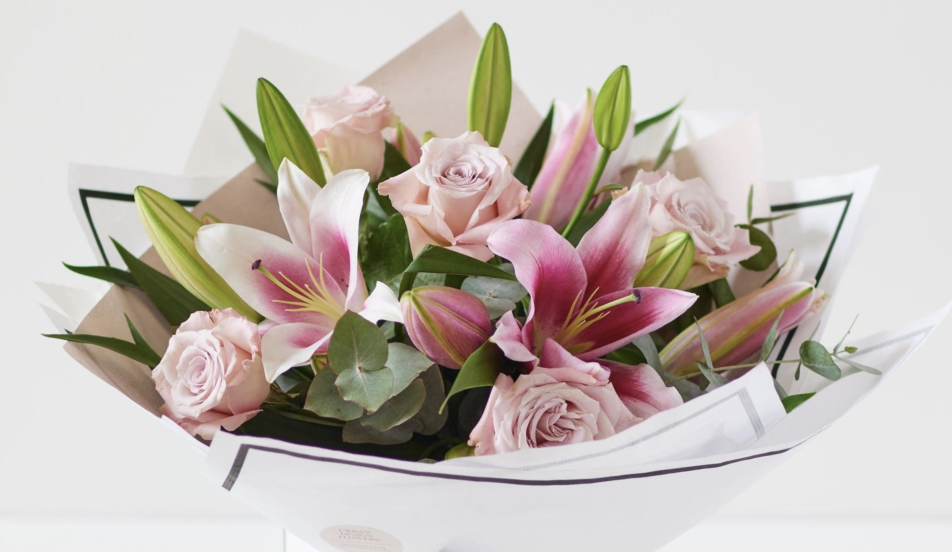 Bouquet of pink roses and lilies wrapped in white paper