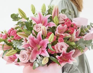 Pink lilies and roses in a hand-tied bouquet