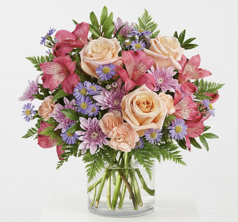 Bouquet of peach roses, pink alstroemeria, and purple daisies in a glass vase