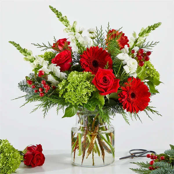 Red roses and gerbera daisies in a glass vase with white snapdragons