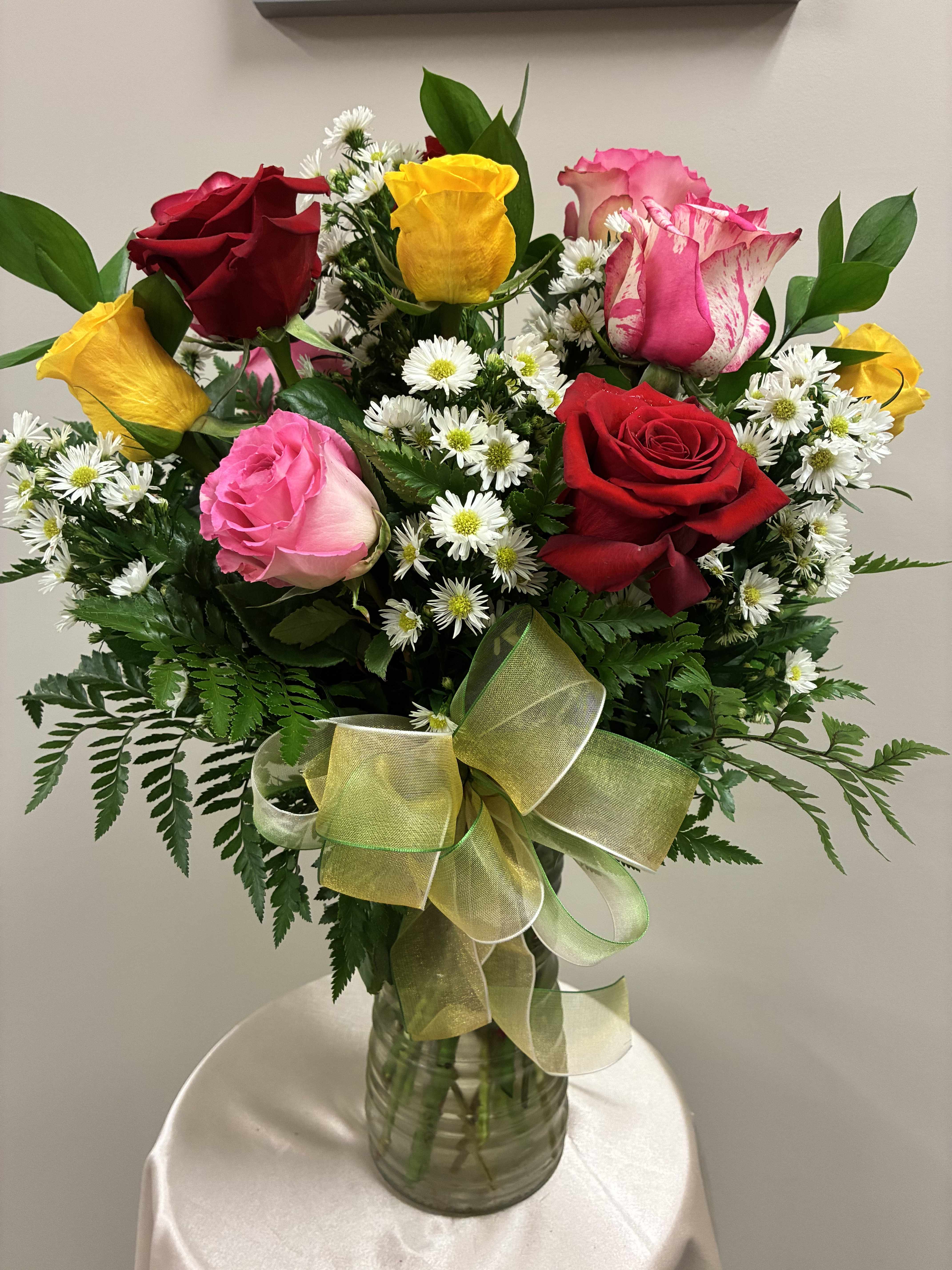 Bouquet of multicolored roses and white daisies in a glass vase