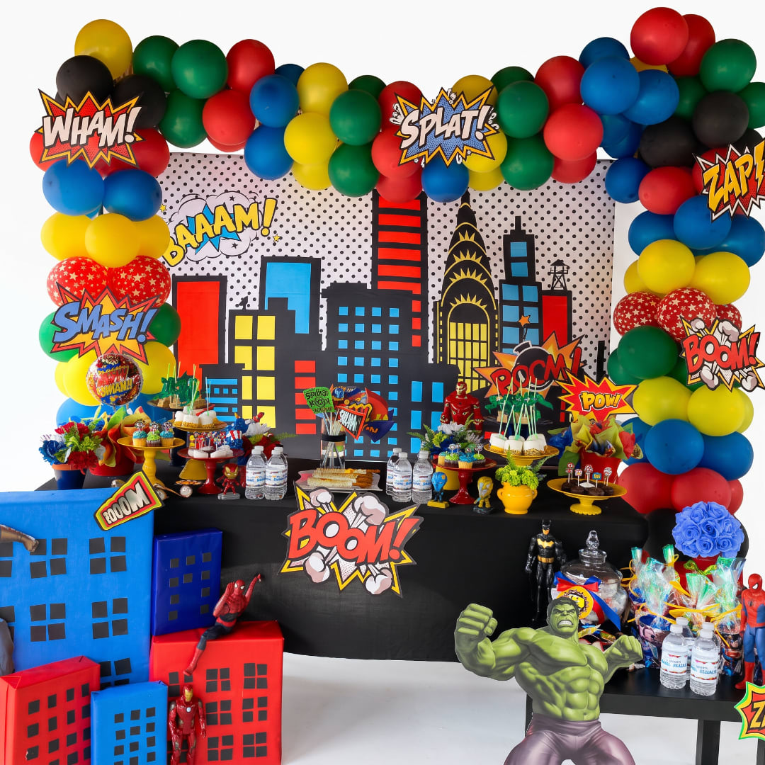 Superhero-themed party display with balloons, comic signs, and dessert tables