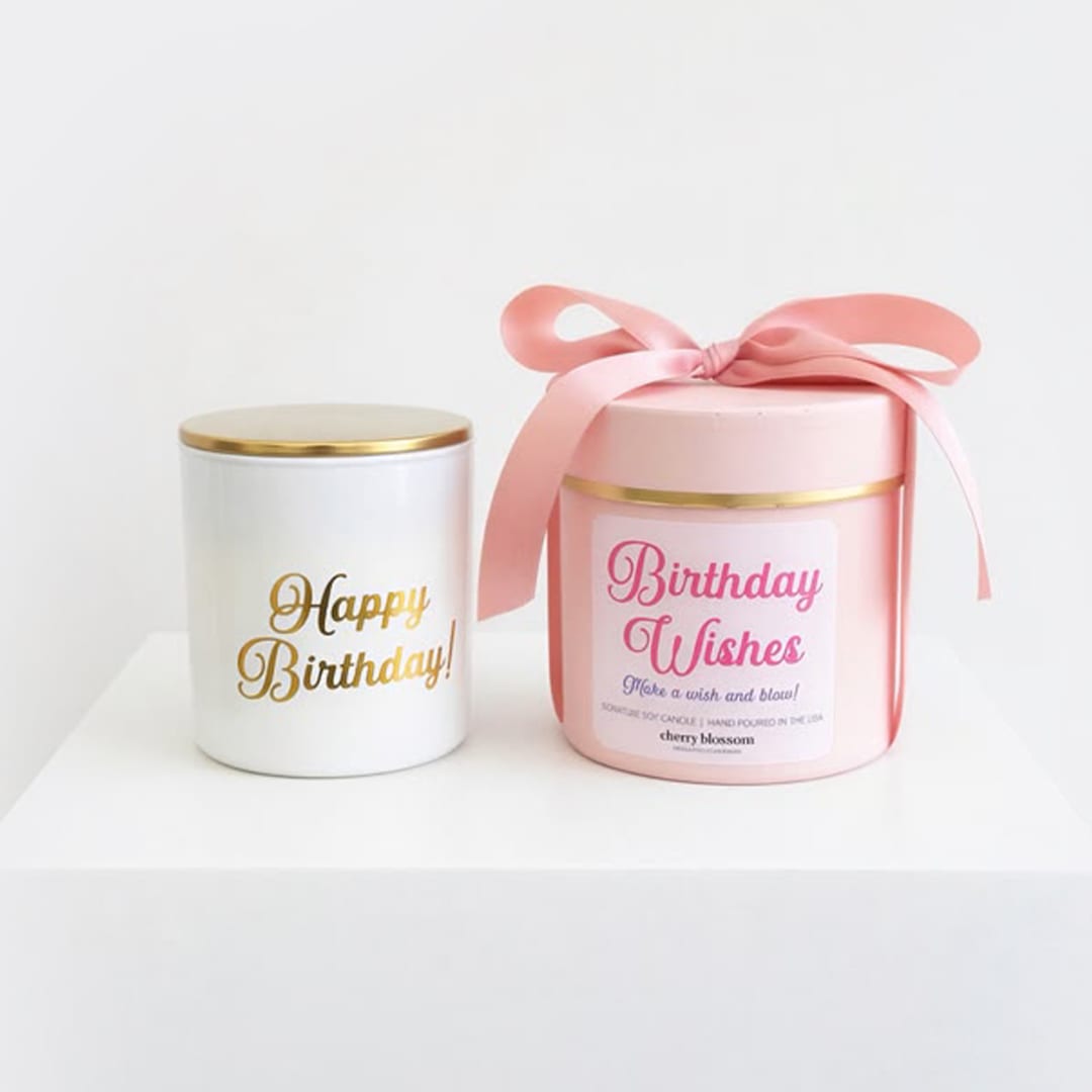 Two birthday candles in white and pink tins with ribbon