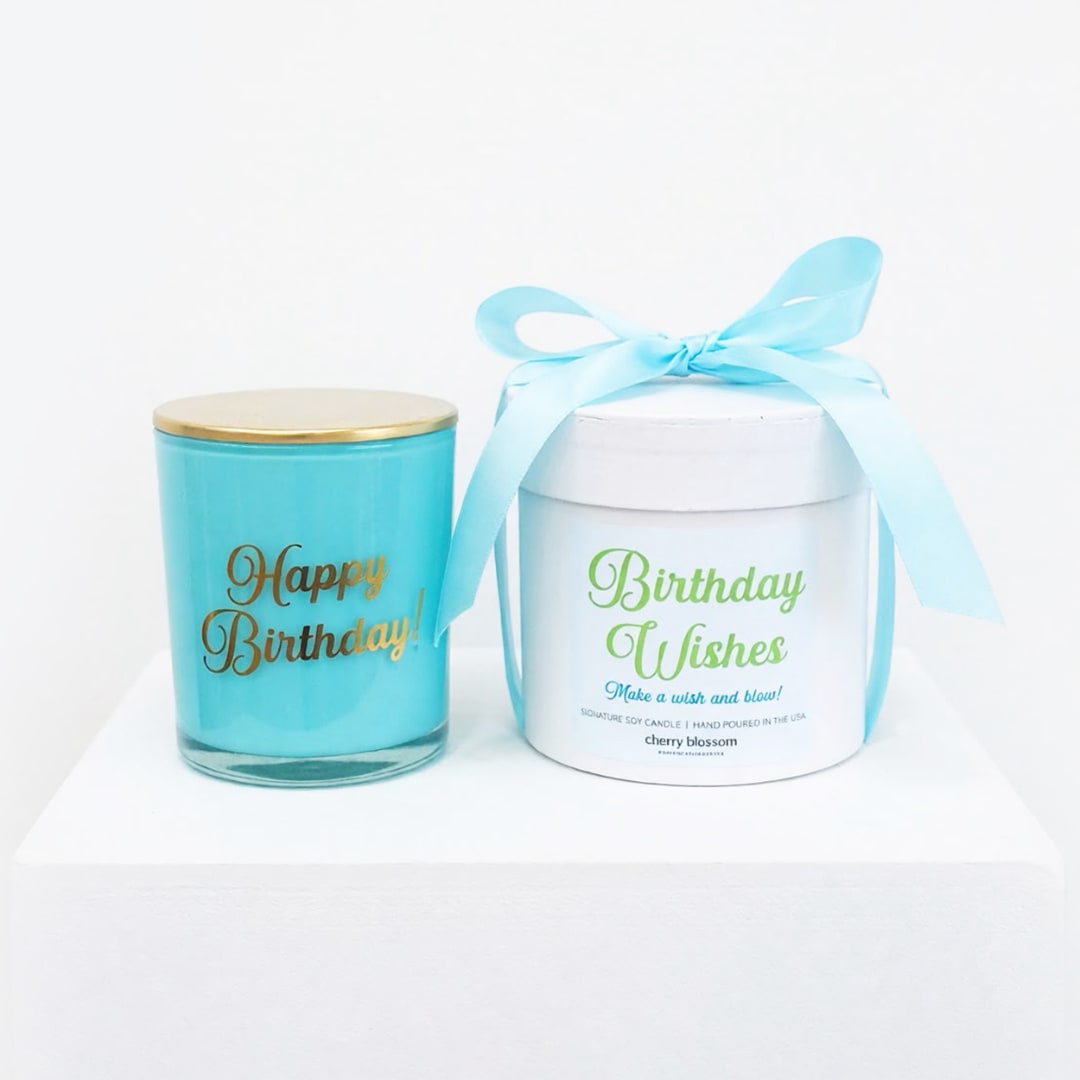 Two birthday candles in jars, one tied with a blue ribbon