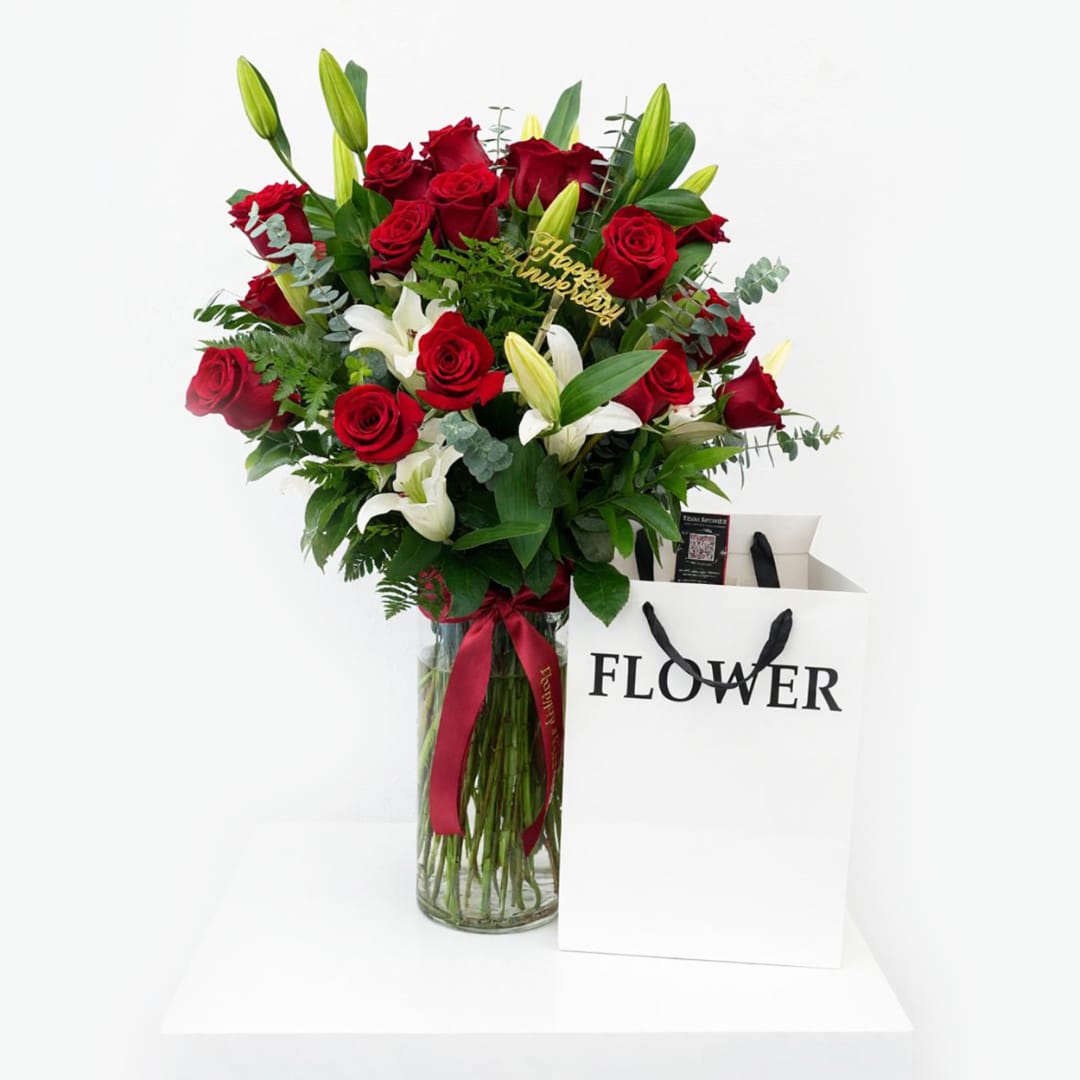 Red roses and white lilies in a glass vase with a ribbon