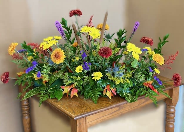 Colorful floral arrangement with yellow, purple, and red blooms on a wooden table