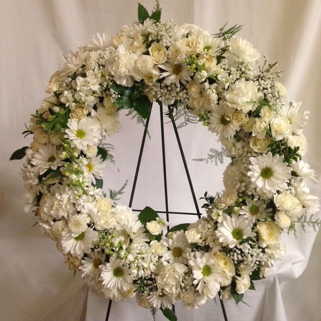 White floral wreath on a black stand