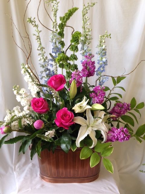 Tall mixed floral arrangement with pink roses and white lilies in a copper container