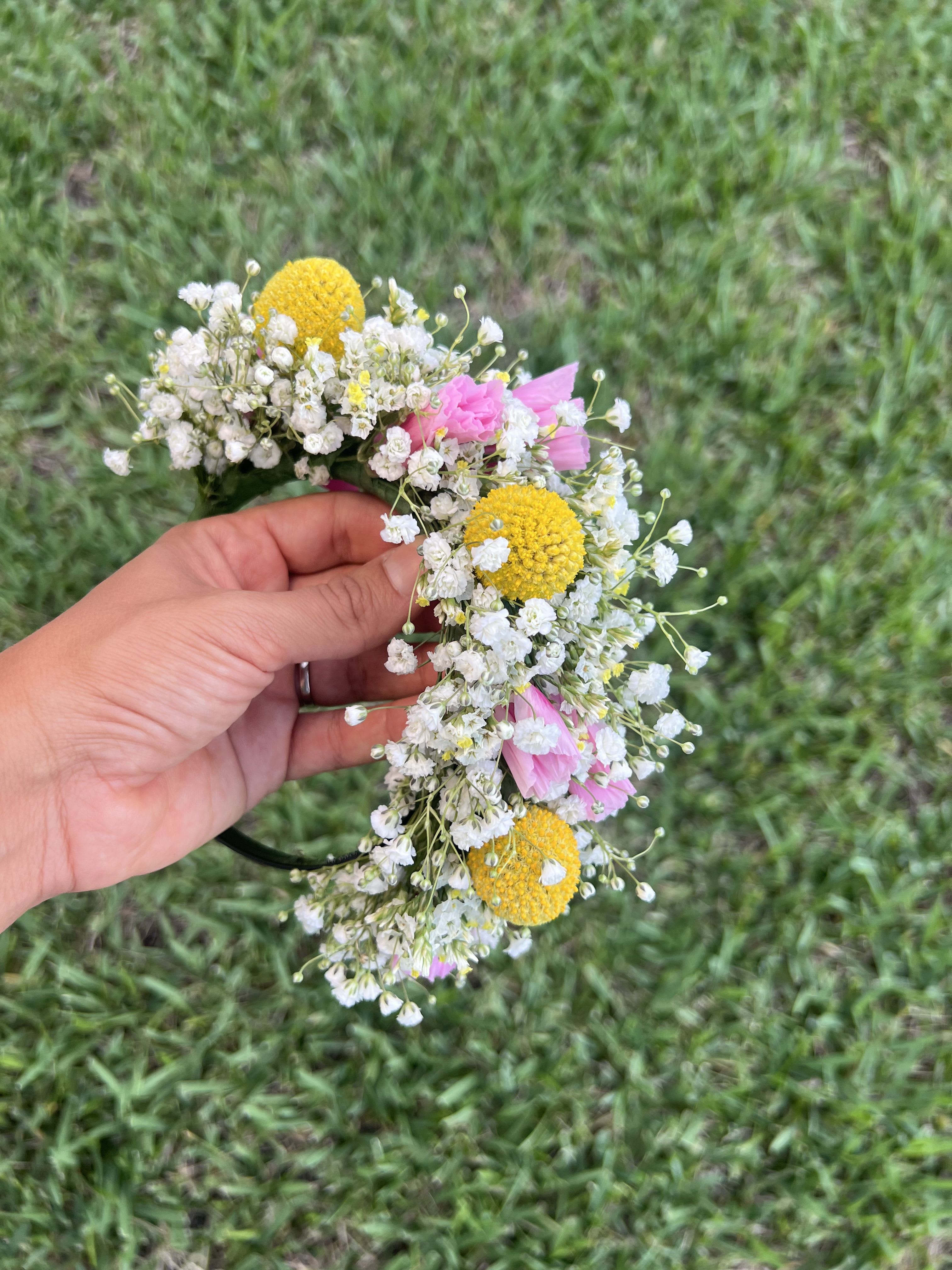 Handheld flower crown with white baby's breath, yellow blooms, and pink flowers
