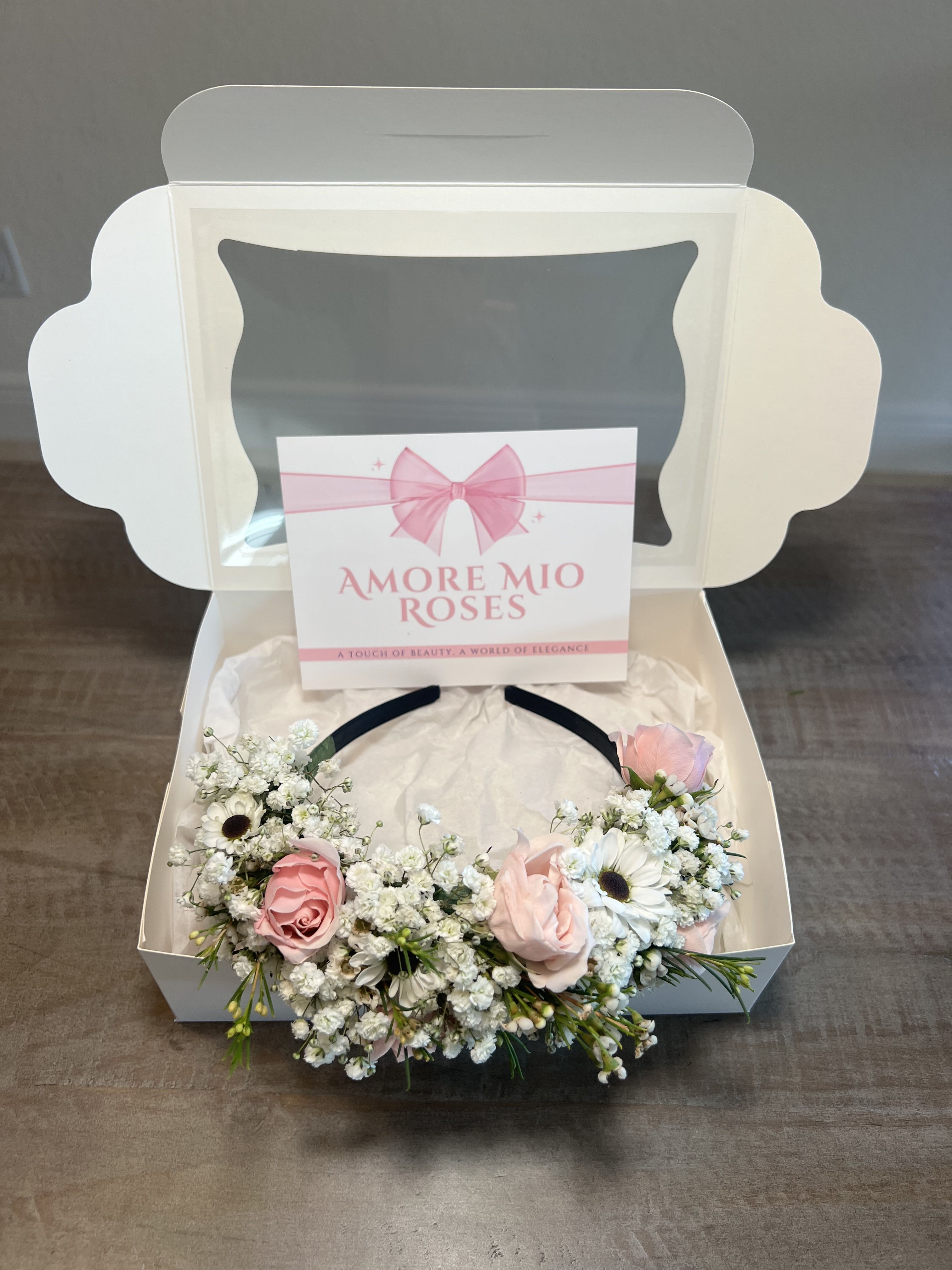 Pink roses and white daisies arranged in a gift box with a ribbon card