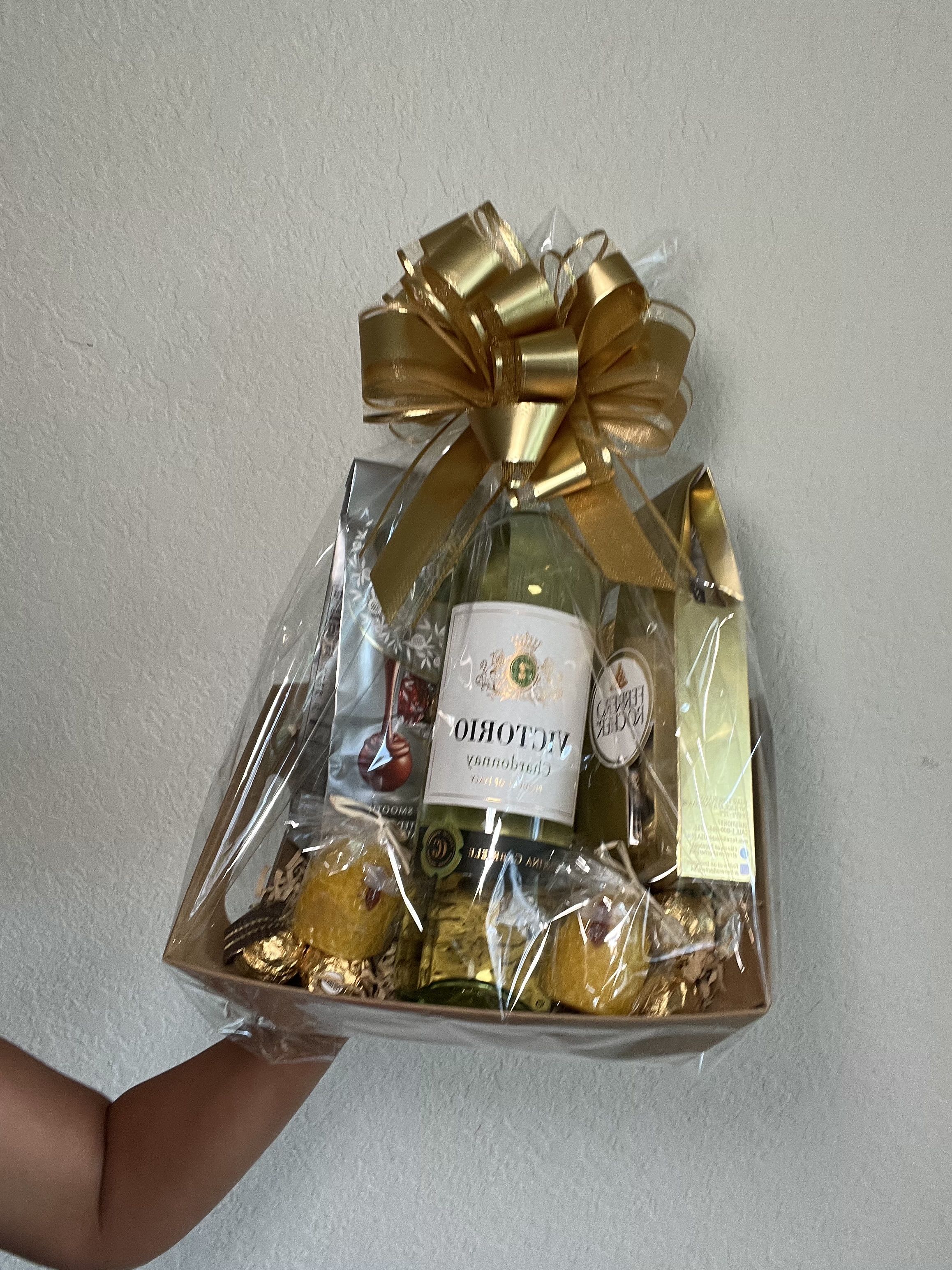 Gift basket with wine bottles, chocolates, and a gold bow