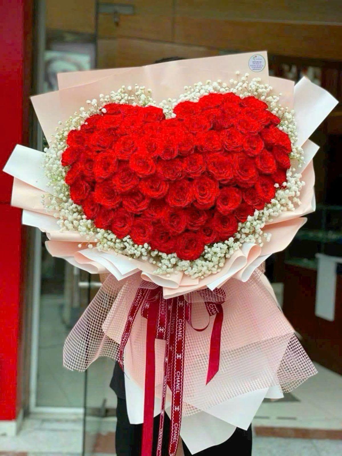 ramo bouquet By Special Moment´S - A lush heart-shaped bouquet built from tightly packed red roses edged in delicate white filler-perfect as an anniversary roses bouquet or a romantic gift to say "I love you." The heart motif and rich red-and-white contrast create an immediate emotional impact: the person you're thinking of will feel cherished and celebrated the moment they see it.  Wrapped in layered pale pink and white paper with a sheer mesh overlay, the arrangement is finished with a decorative mesh ribbon and long red ribbons that trail below for a polished, gift-ready presentation. The mix of classic roses with soft white accents and feminine pink wrapping gives the bouquet depth, texture, and a timeless romantic look.  Designed for love-themed occasions-anniversaries, Valentine's Day, or any moment you want to make unforgettable-this bouquet arrives ready to present and makes a bold visual statement. Handle with care: keep stems in water, away from direct heat and sunlight to extend freshness; if ordering for a specific date, choose delivery timing to ensure it arrives at peak bloom.