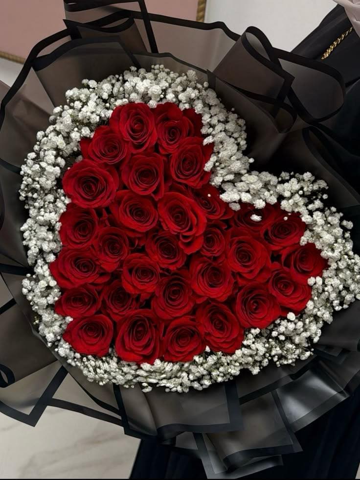 ramo bouquet de rosas By Special Moment´S - A tight cluster of velvety red roses contrasted by a halo of delicate white baby's breath creates dramatic romance in this rose bouquet for Valentine's Day, anniversaries, or any moment you want to make someone feel deeply cherished. The bold color play-scarlet petals against airy white filler and a statement black wrap-gives the arrangement a formal, polished look that reads as both classic and modern; the person you're gifting will feel seen and celebrated the moment they hold it.  Hand-tied roses are arranged in a rounded, symmetrical shape and finished in black wrapping paper with a black ribbon for a striking, high-contrast presentation. The bouquet's compact, dense form emphasizes the rich texture of the roses and the light, cloud-like feel of the baby's breath, making it an ideal size for hand delivery or a memorable centerpiece on an intimate table.