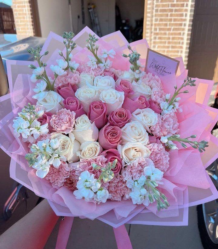 ramo buchon de rosas By Special Moment´S - A lush, full-bodied bouquet of pink and white roses that reads as pure romance-this ramo buchón de rosas is ideal for an anniversary, birthday, or a heartfelt just-because surprise. The tightly packed, plush silhouette and soft pastel palette create an immediate impression of warmth and affection so the person you're thinking of will feel truly celebrated the moment they see it.  Clusters of pale pink carnations and tiny white filler blooms weave through the roses for delicate texture and visual depth. The arrangement is finished in layered pink tissue wrap with a long pink ribbon and includes a card, giving it a polished, gift-ready presentation. Colors: pink, white, mixed; flowers: roses, carnations, and complementary blooms.  Perfect for someone who loves romantic, feminine florals-this bouquet makes a thoughtful gesture that suits birthdays, anniversaries, or spontaneous moments of appreciation. Order notes and sizing are shown at checkout; to keep blooms fresh, place in clean water and trim stems if desired.