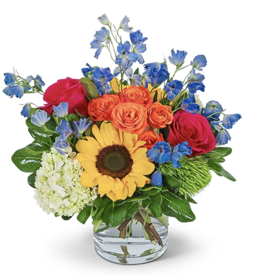 Mixed bouquet with sunflowers, roses, and blue flowers in a glass vase