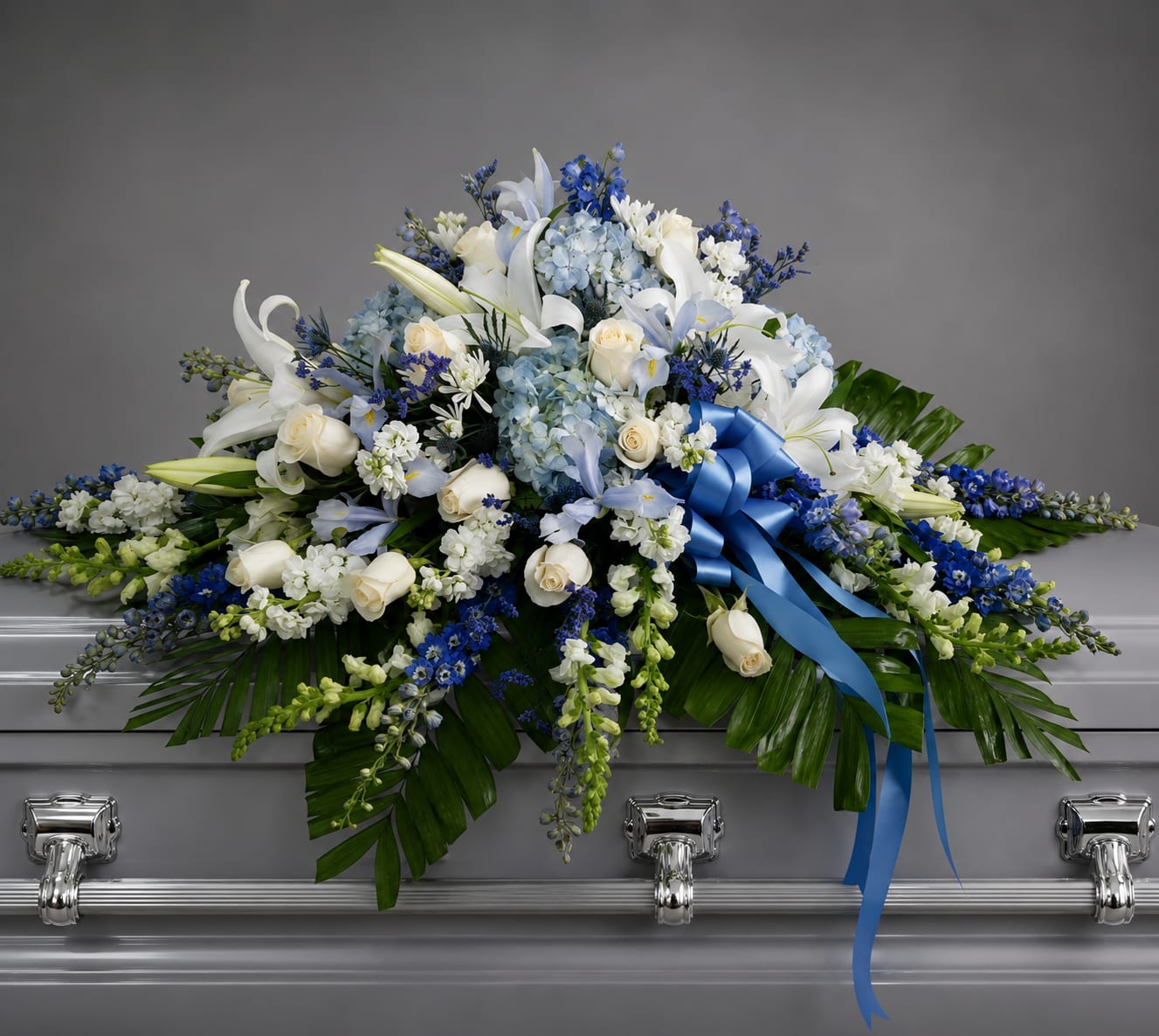 Blue and white floral casket spray with a satin ribbon