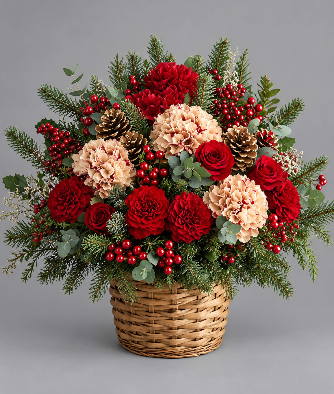 Basket arrangement of red and peach carnations with pinecones and berries