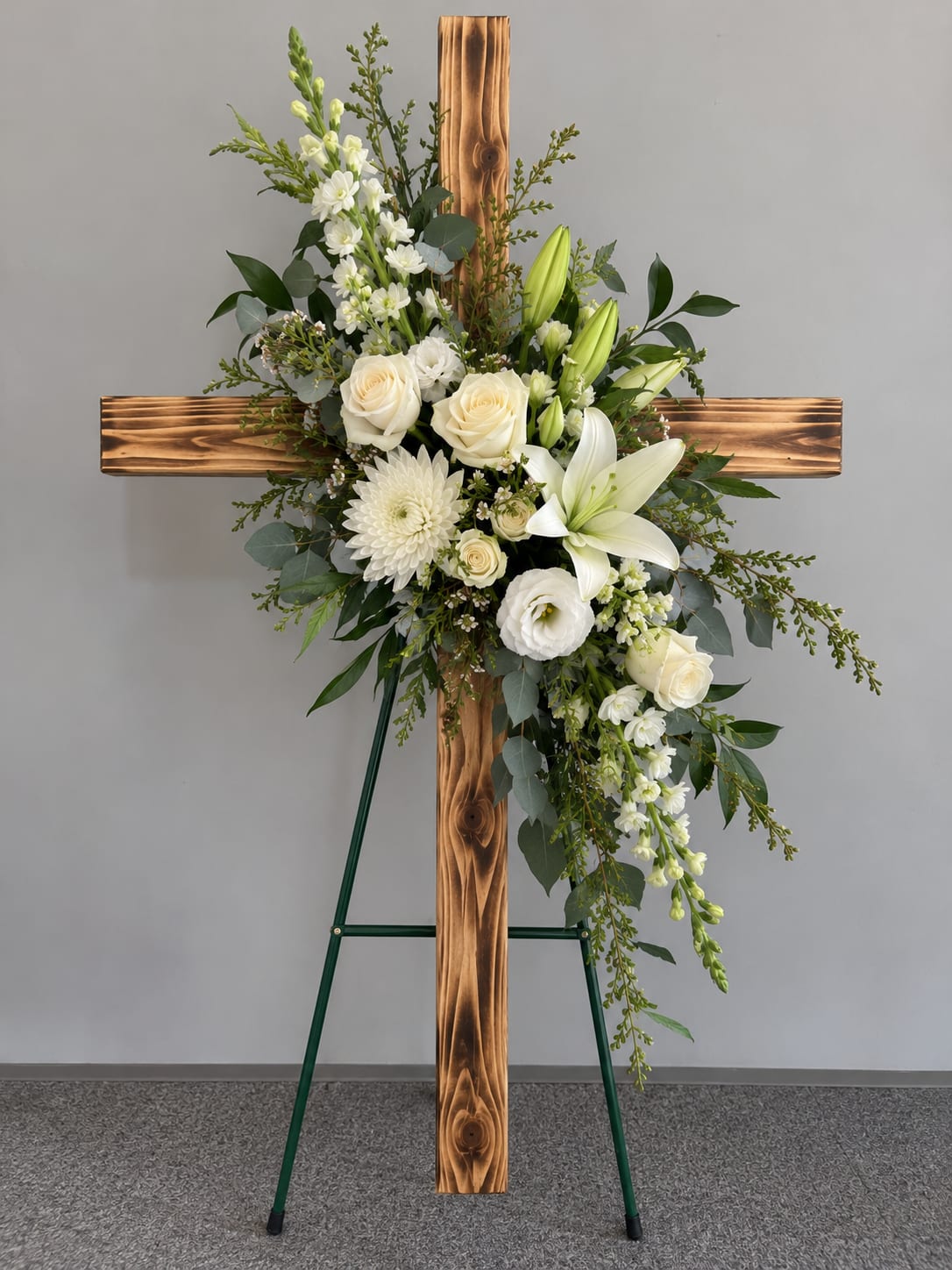 White floral spray arranged on a wooden cross