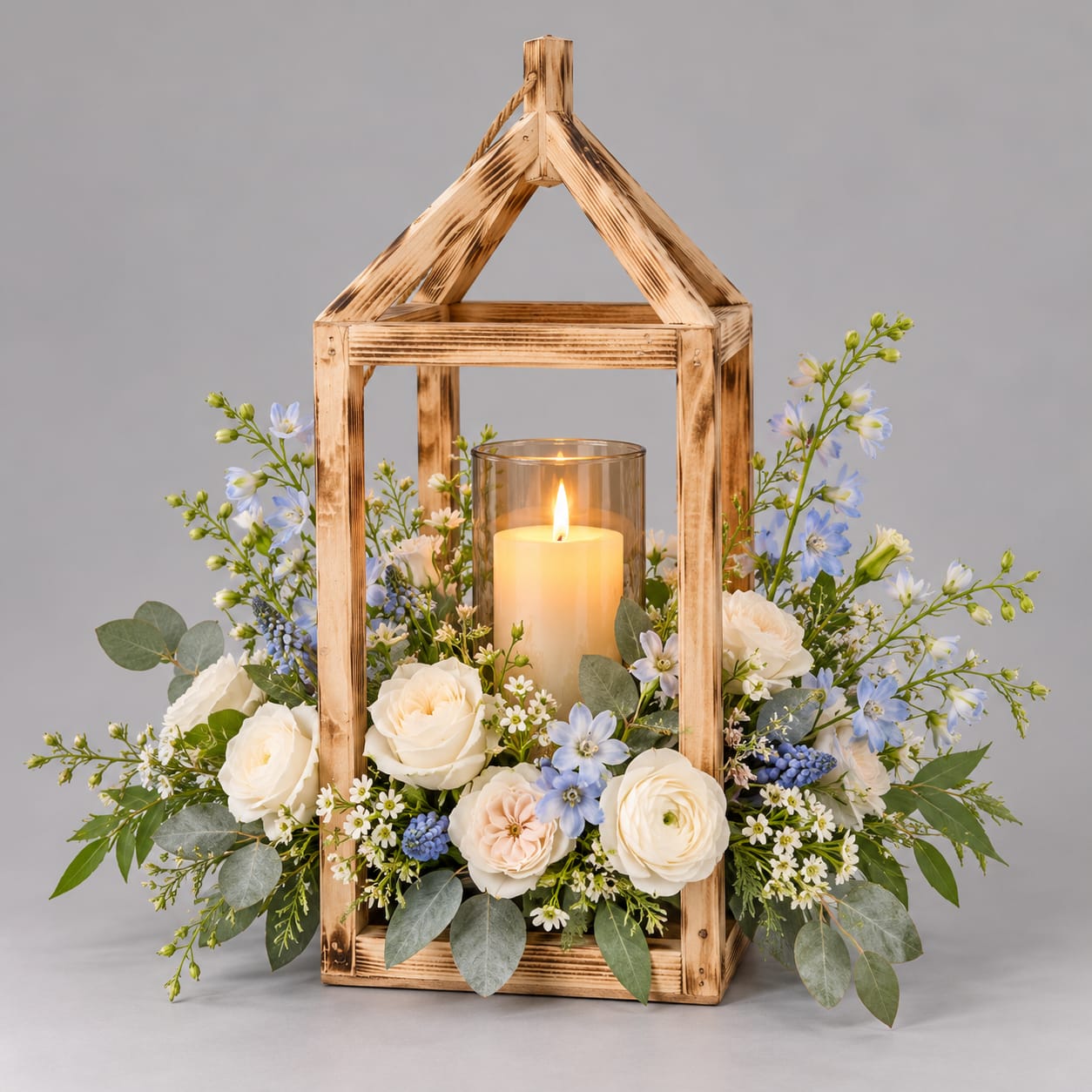 Wooden lantern centerpiece with a lit candle and white and blue flowers