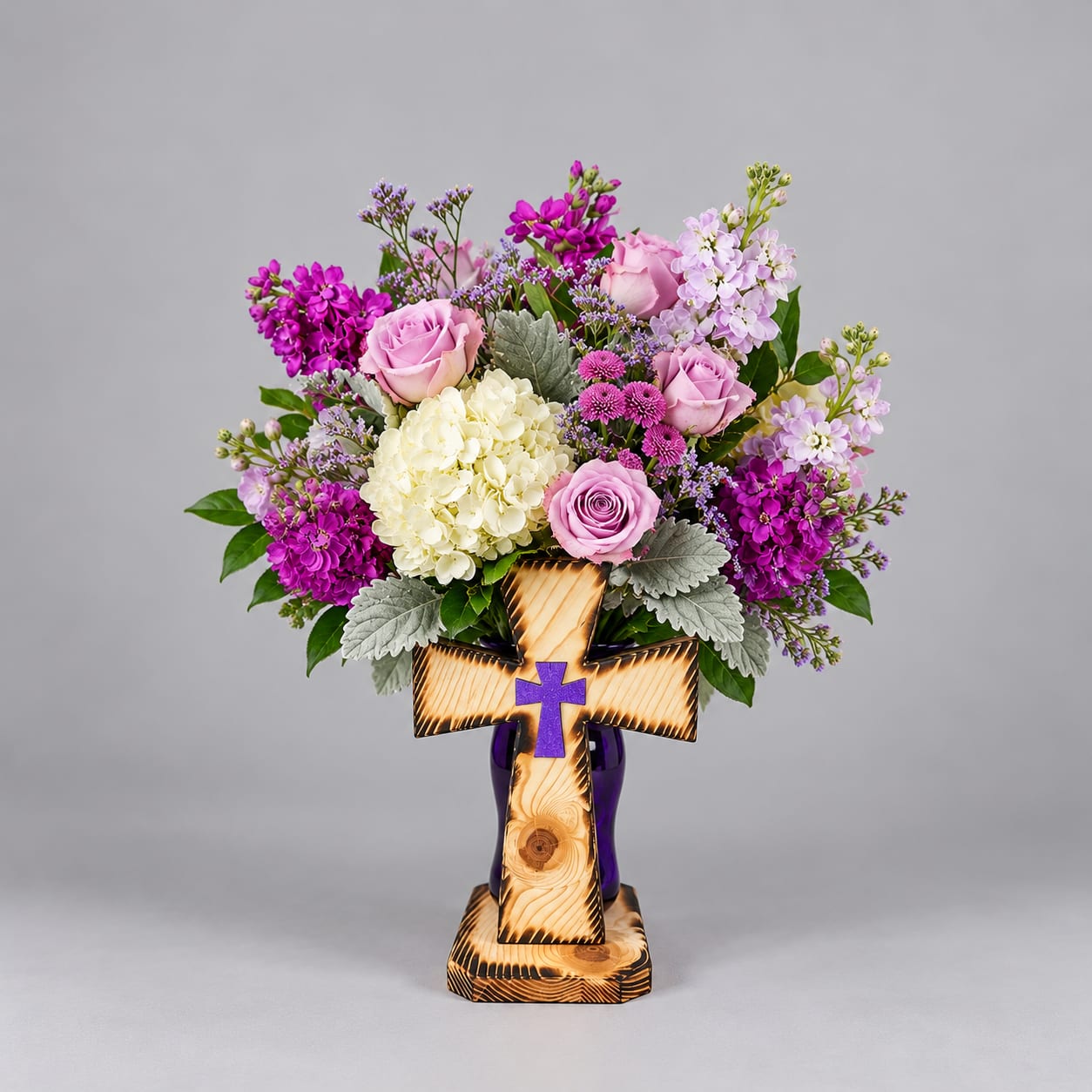 Pink and purple flower arrangement in a wooden cross vase
