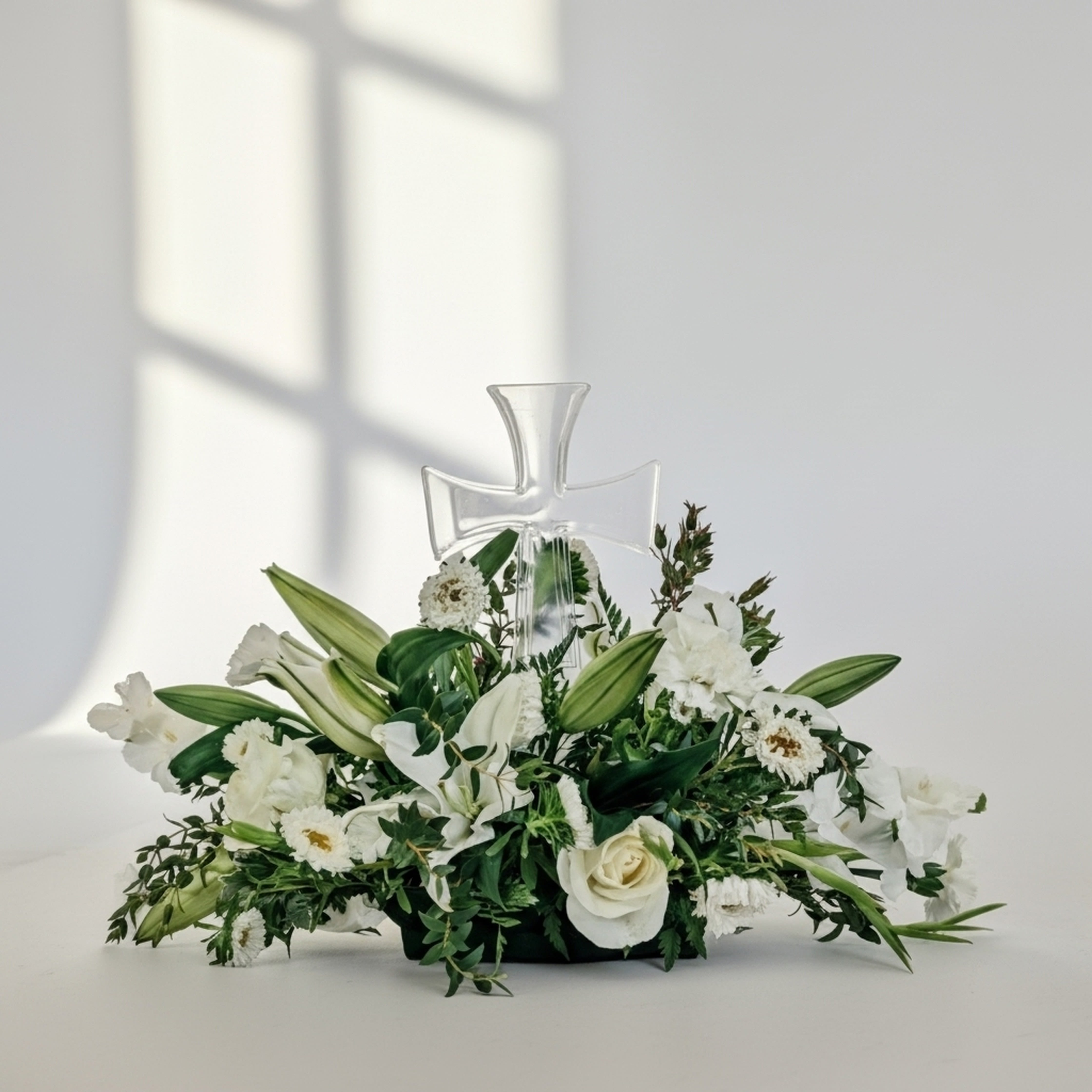 White floral arrangement with a clear cross centerpiece