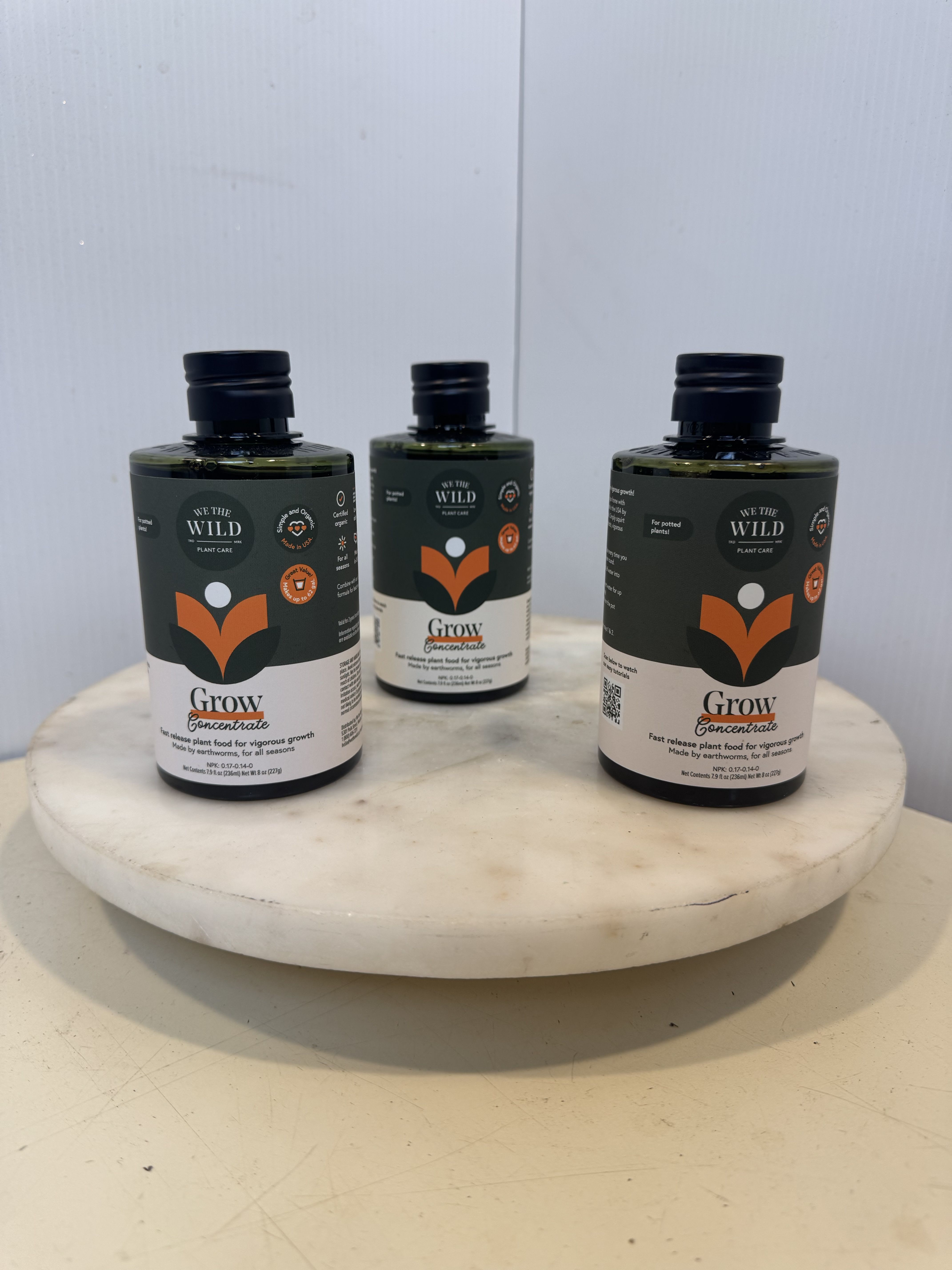Three plant care bottles on a round white pedestal