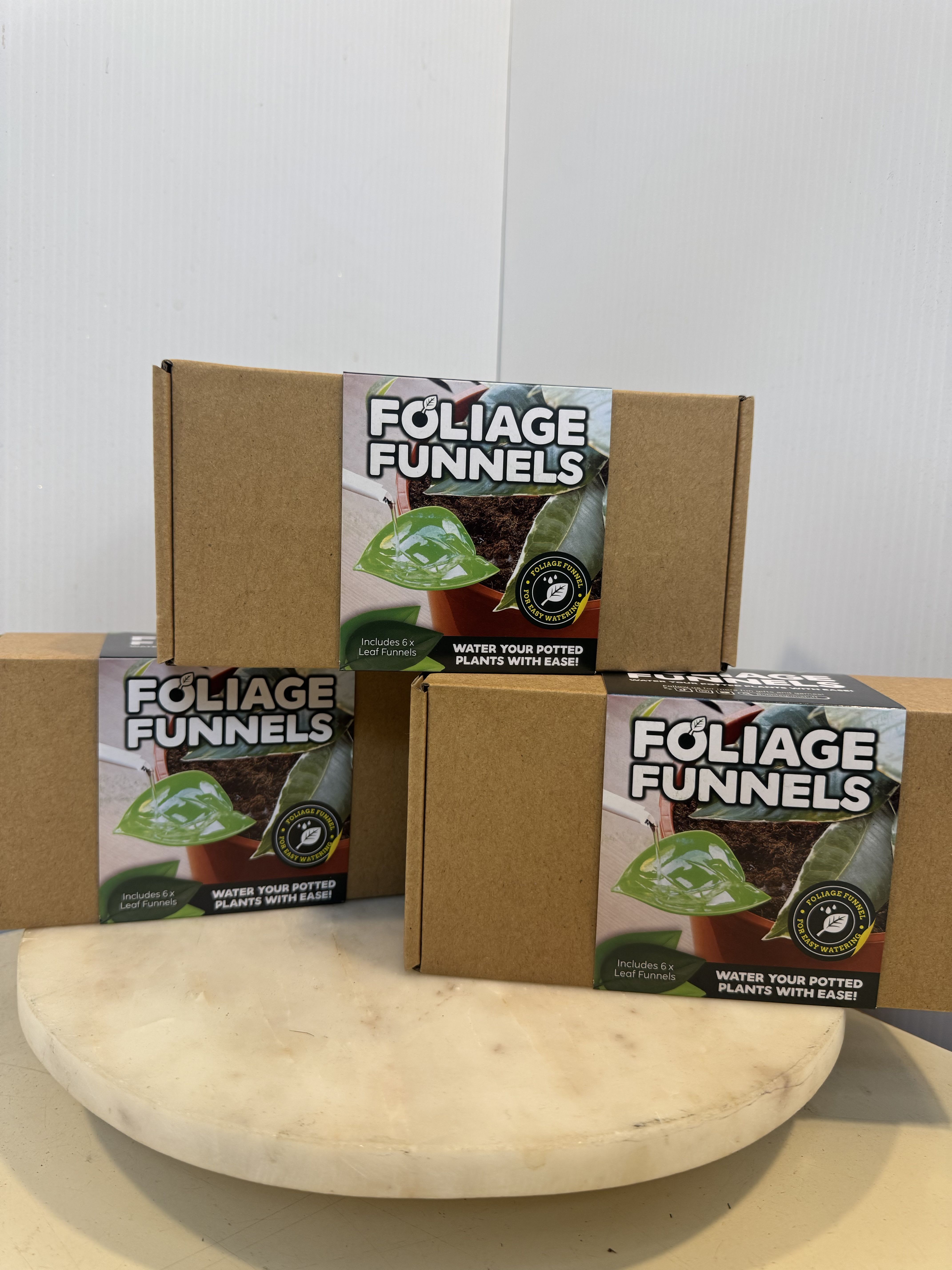 Three cardboard boxes of foliage funnels stacked on a round pedestal.