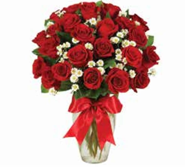 Bouquet of red roses with small white filler flowers in a glass vase