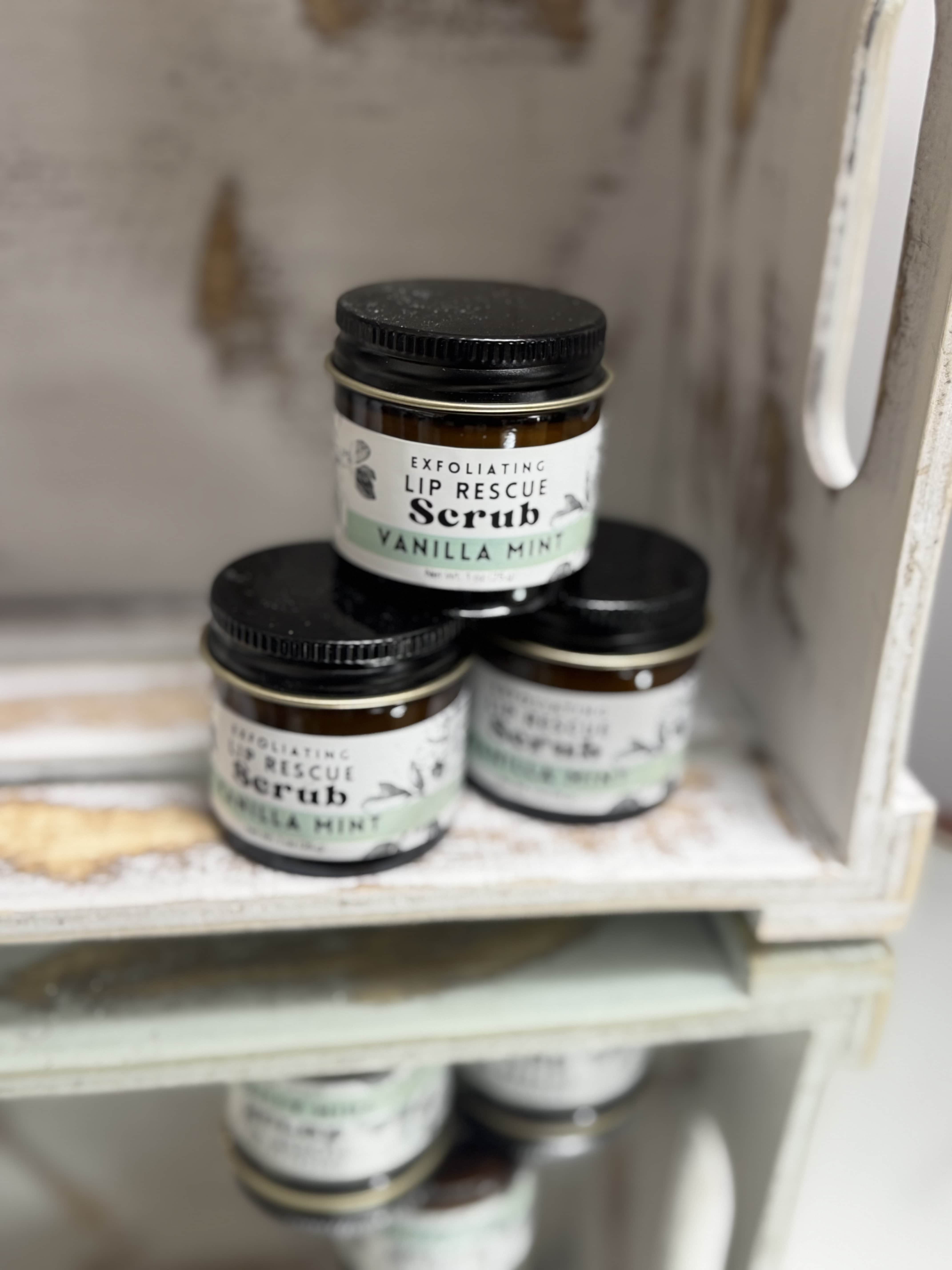 Three jars of vanilla mint lip scrub stacked on a shelf