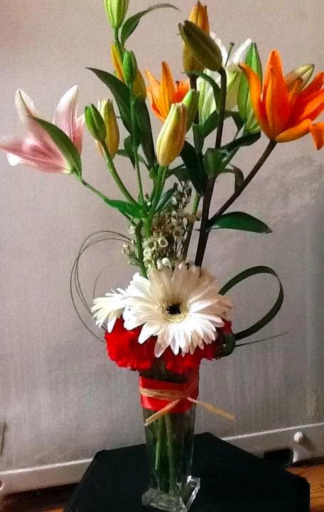 Tall bouquet of lilies and gerbera daisies in a clear glass vase
