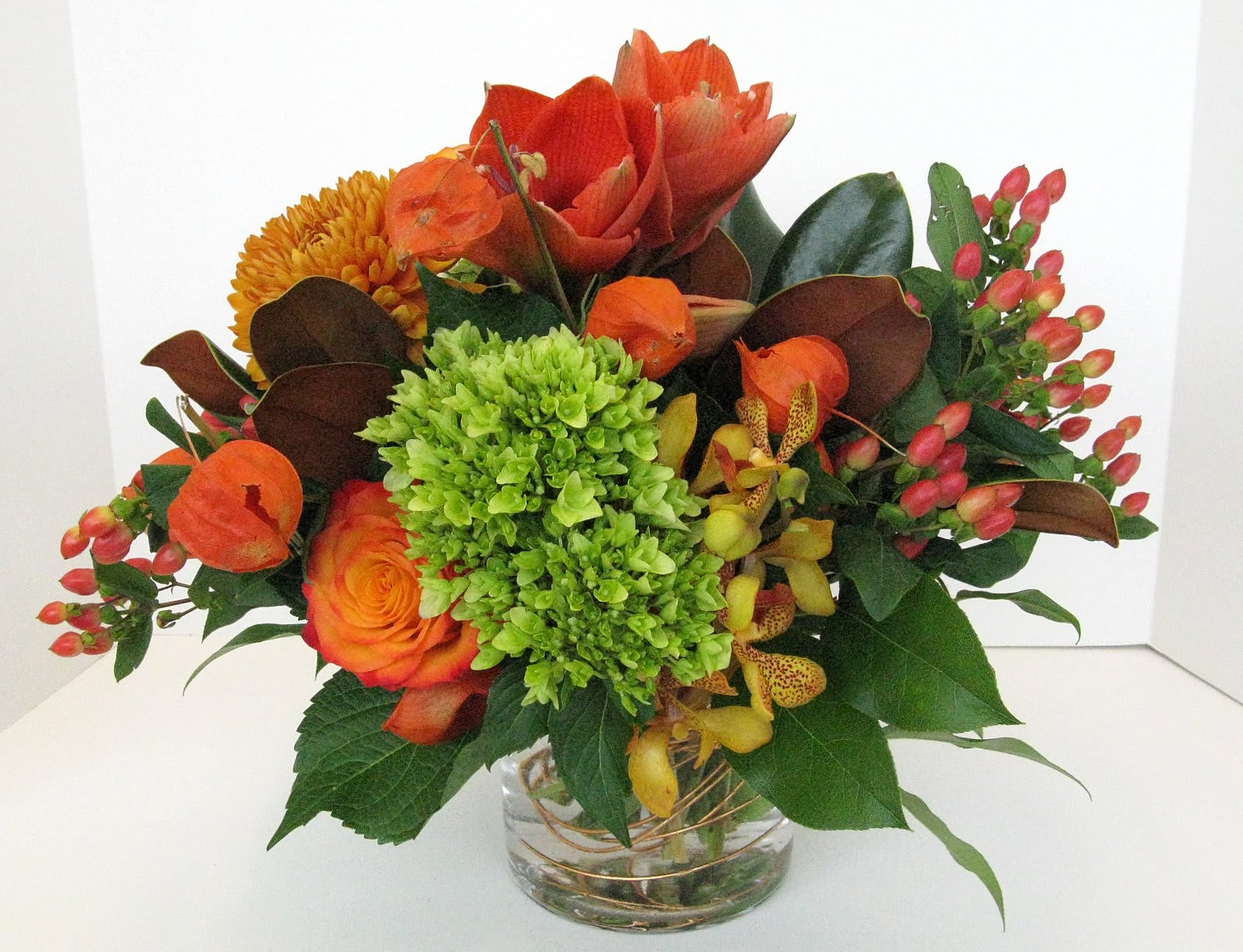 Orange and green mixed bouquet in a clear glass vase