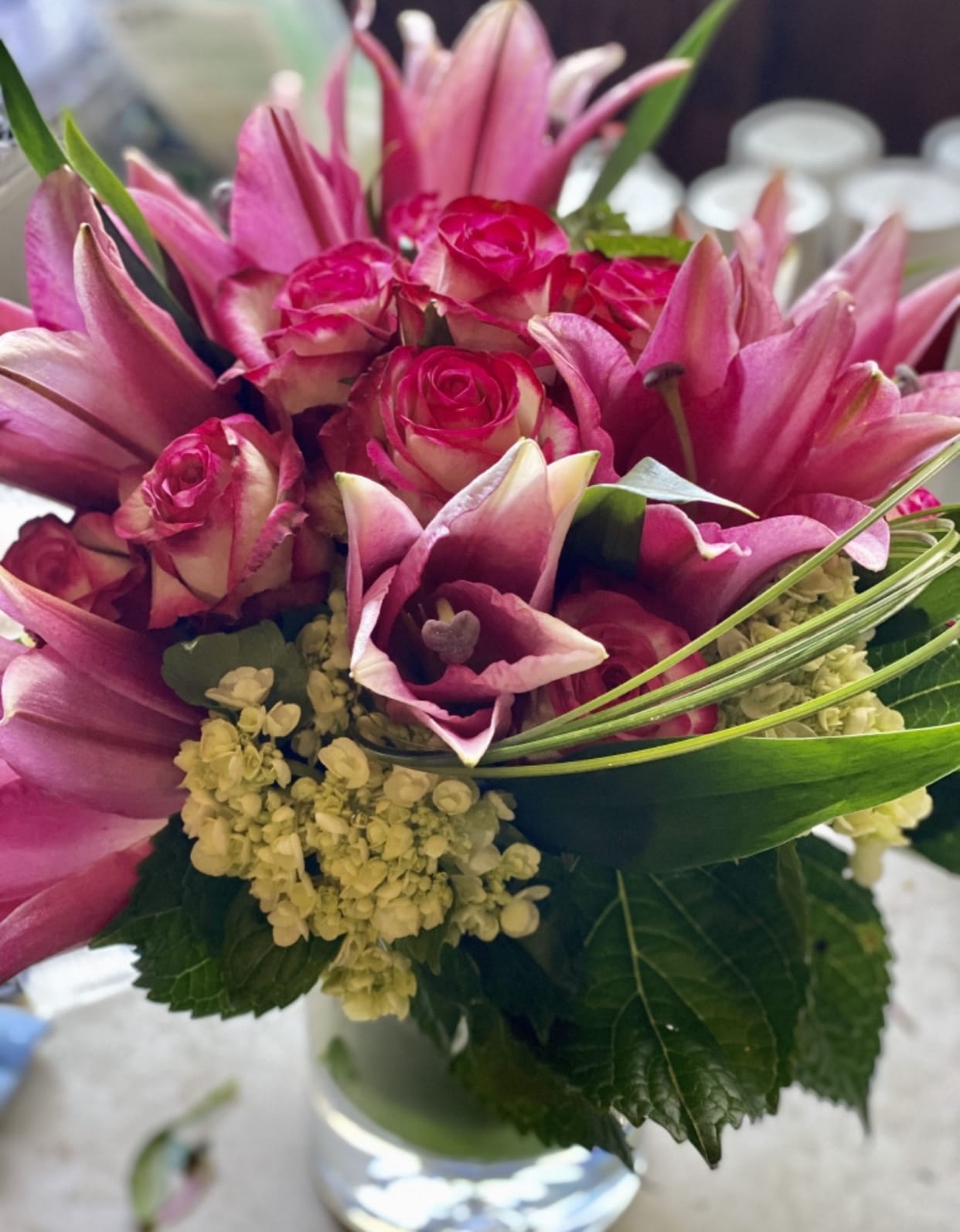 Pink roses and lilies arranged in a clear glass vase