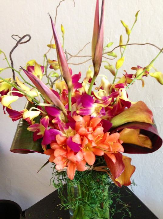 Bright tropical flower arrangement with orchids and calla lilies in a vase