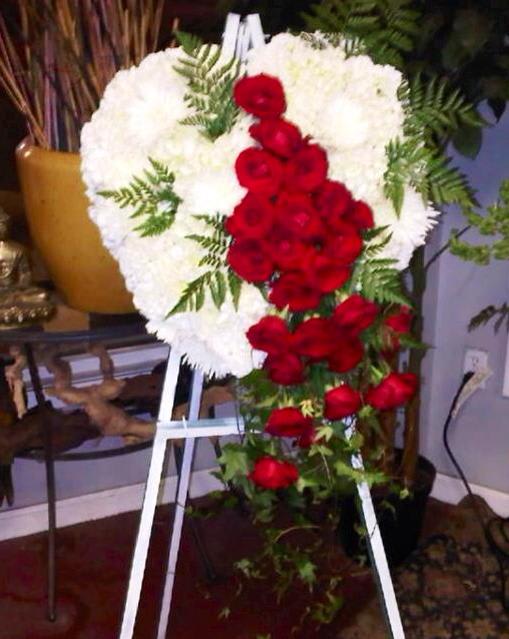 Heart-shaped floral spray of white and red roses on an easel