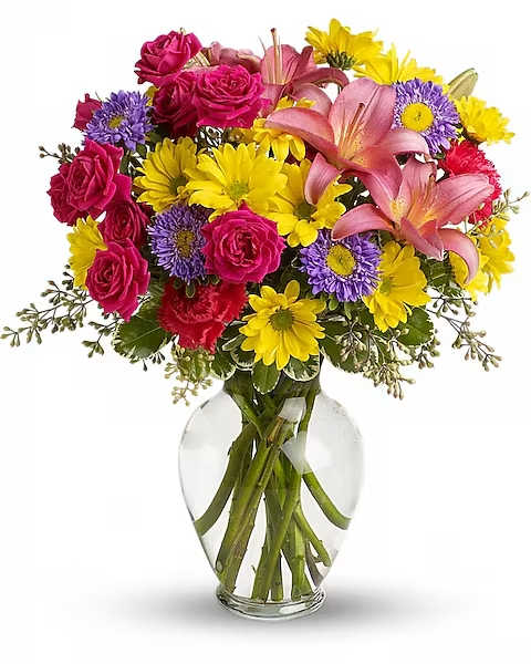 Bouquet of pink roses, lilies, and yellow daisies in a clear glass vase