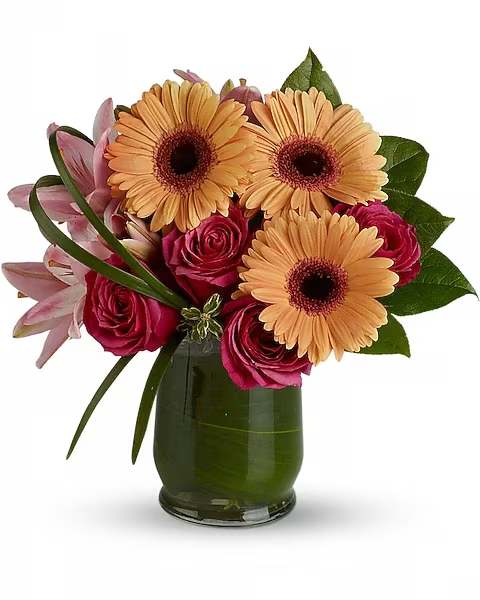 Bouquet of peach gerbera daisies and pink roses in a green glass vase