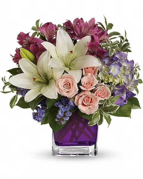Bouquet of white lilies, pink roses, and purple flowers in a purple vase