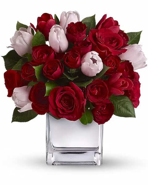 Red and pale pink roses arranged in a clear glass vase
