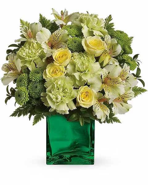 Green and yellow floral arrangement in a square glass vase
