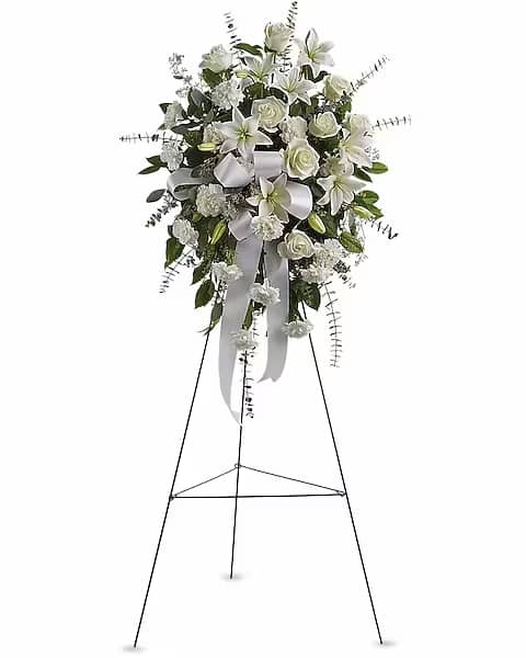 White floral standing spray on a metal easel with ribbon