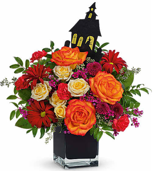 Halloween bouquet with orange and red roses in a black vase, topped with a haunted house pick