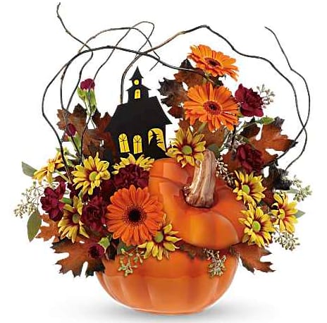 Pumpkin-shaped floral arrangement with orange and burgundy flowers and a small haunted house pick